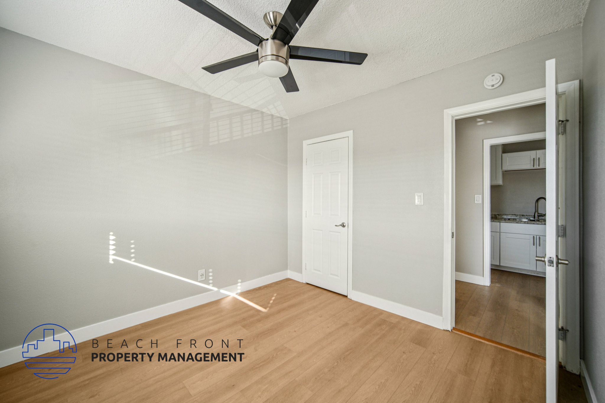 A room with a ceiling fan and a door leading to another room.